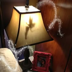 a lamp that is on top of a night stand next to a bed with a picture frame