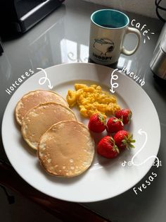 pancakes, scrambled eggs and strawberries are on a plate with a cup of coffee