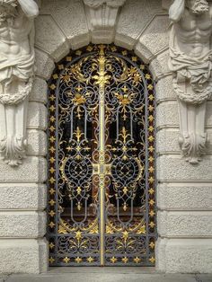 an ornate iron gate with lion heads on the side of a stone building in front of a doorway