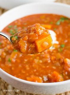 a spoon full of soup with carrots and parsley