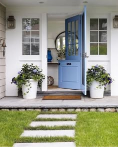 an instagram photo with blue door and flowers on the front steps in front of a house