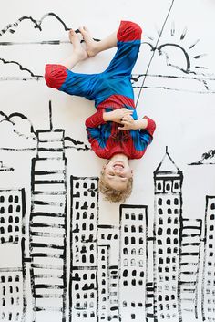 a young boy is upside down on the ground in front of a cityscape