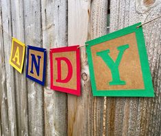 the letters and y are made out of construction paper on a clothes line that is hanging from a wooden fence