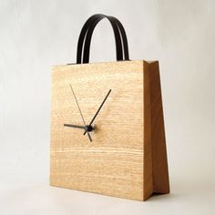 a clock made out of wood sitting on top of a white table next to a bag