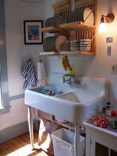 a white sink sitting under a shelf filled with dishes