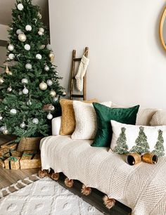 a living room with a christmas tree in the corner and decorations on the couches