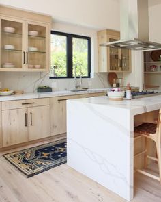 a kitchen with wooden cabinets and white marble counter tops, along with a rug on the floor