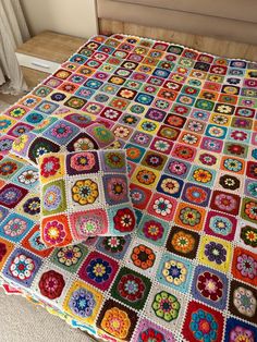 a crocheted granny blanket on top of a bed in a room with a window