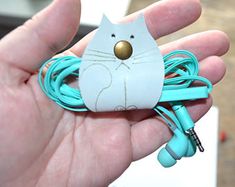 a person holding a cat shaped earbud in their hand