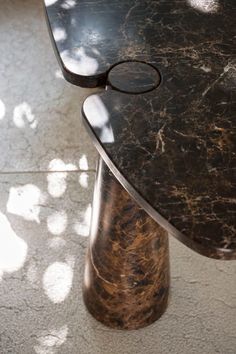 a marbled table with an oval shaped top and curved legs, in the sunlight