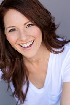 a woman smiling and wearing a white shirt