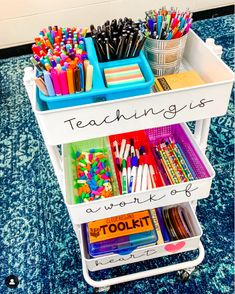 a white cart filled with lots of different colored pens and pencils on top of a blue carpet