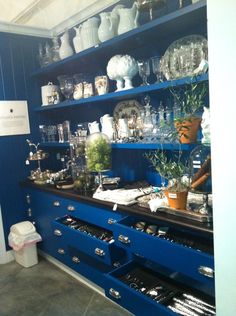 a blue shelf filled with lots of vases and other items on top of it