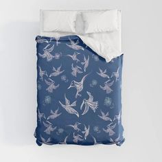 a bed with blue and white birds printed on the comforter, along with two pillows