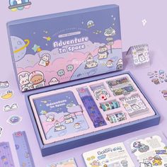 an assortment of stickers and magnets in a box on a purple surface with other items