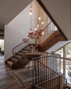 an image of a stair case with lights hanging from the ceiling and flowers in a vase on the table