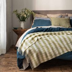 a bed with blue and green plaid comforter in a bedroom next to a window