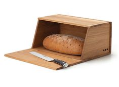 a loaf of bread in a wooden box with a knife