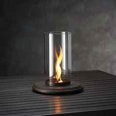 a lit candle sitting on top of a table next to a glass vase filled with fire