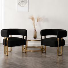 two black chairs sitting next to each other in front of a table with a vase on it