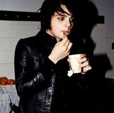 a man in black leather jacket holding a cup