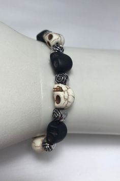 "This is a handmade skull and roses bead elastic bracelet.                                                                     The skulls are black and white with silver roses in between.                                                                   This bracelet is 7\" unstretched.                                                                                                                   Please feel free to contact me with any questions or concerns." Cheap White Bracelet For Halloween, Halloween Skull Bracelets With Skull Print, Halloween Skull Print Bracelet Gift, Gothic Skull Print Bracelets As Gift, Adjustable Gothic Skull Bracelets, Adjustable Handmade Skull Bracelets, Handmade Casual Skull Bracelets, Handmade Casual Skull Bracelet, Casual Handmade Skull Bracelets