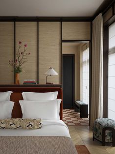 a bed with white sheets and pillows next to a window in a room filled with furniture