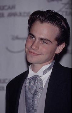 a young man in a suit and tie smiling for the camera at an event,