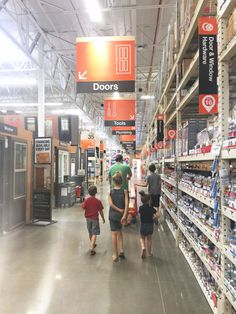 people are walking through the aisle of a grocery store with shelves full of goods and signs