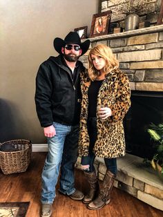 a man and woman standing next to each other in front of a fire place wearing cowboy hats