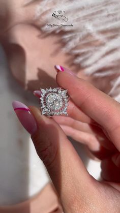 a woman's hand holding an engagement ring with pink and white manicured nails