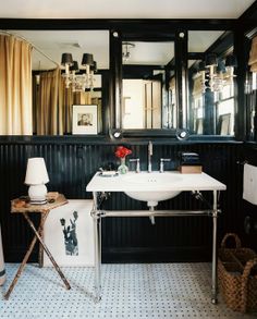 a white sink sitting under a bathroom mirror next to a bath room with black walls