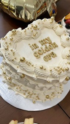 a heart shaped cake on a table with gold foil and other food items around it