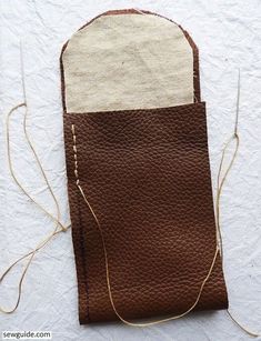 a piece of brown leather with white stitching on the front and side, sitting on a white surface