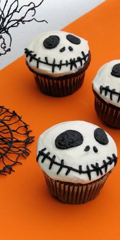 three cupcakes with white frosting and black icing decorated to look like skeletons