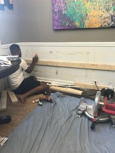 a man is sitting on the floor working on some wood planks in his home