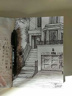 an open book with a drawing of a house and stairs on the front cover, next to a pen