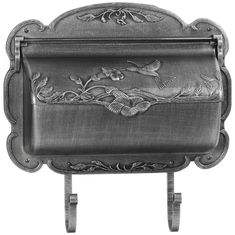 an ornate metal tray with birds and flowers on the front, sitting on a stand