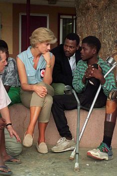 a group of people sitting on top of a cement bench with crutches in front of them