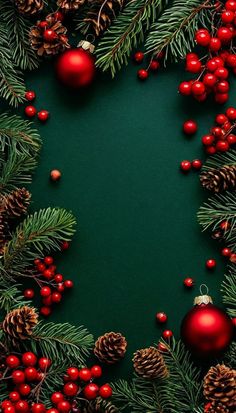 christmas decorations and pine cones are arranged on a dark green background with red berries, firs and evergreen needles