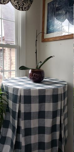 a black and white checkered table cloth with a vase on it in front of a window