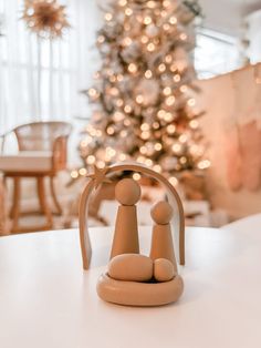 a small wooden figurine sitting on top of a table next to a christmas tree