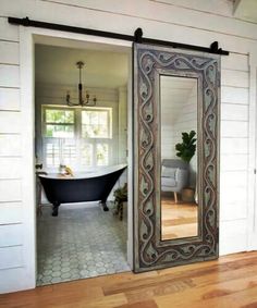 an open door leading to a bathroom with a bathtub in the background and a large mirror on the wall