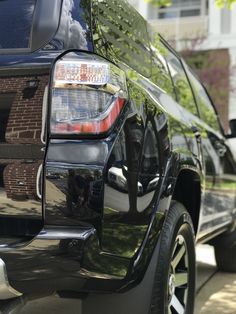 the back end of a black suv parked in front of a house