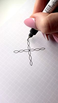 a woman's hand holding a pen over a piece of paper with a cross drawn on it