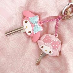 two hello kitty keychains on a pink background