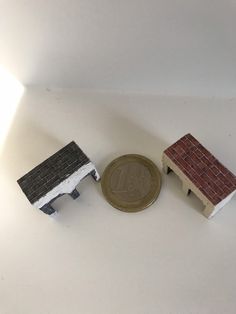 two miniature houses next to a penny on a white surface