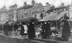 an old black and white photo of people standing in front of some buildings on a city street