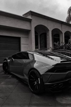 a grey and black sports car parked in front of a house