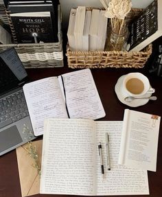 an open book sitting on top of a desk next to a laptop computer and cup of coffee